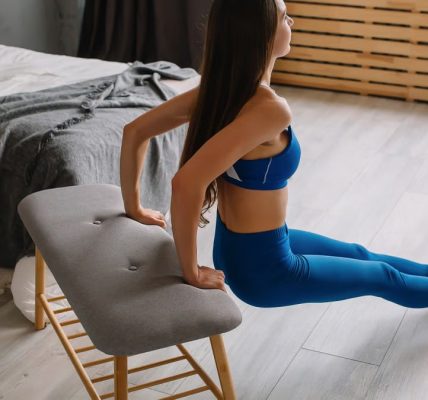 Young woman in sportswear doing tricep dips using bench at home.